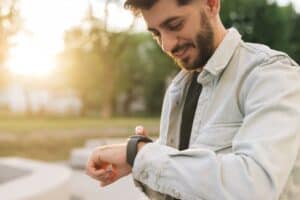 Smartwatch on a man's hand outdoor. Man's hand touching a smart watch. Closeup shot of male's hand uses of wearable smart watch at outdoor. Smartwatch.