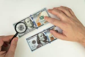 Counterfeiter forges banknotes. Fake concept. Fake money American dollars, magnifier. view money under a magnifying glass. watermark, water mark. search for counterfeit bills