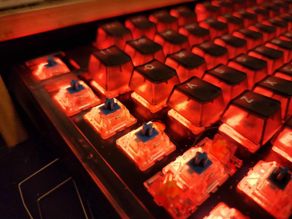 A keyboard with an exposed row of Cherry MX Blue switches and RGB lighting.