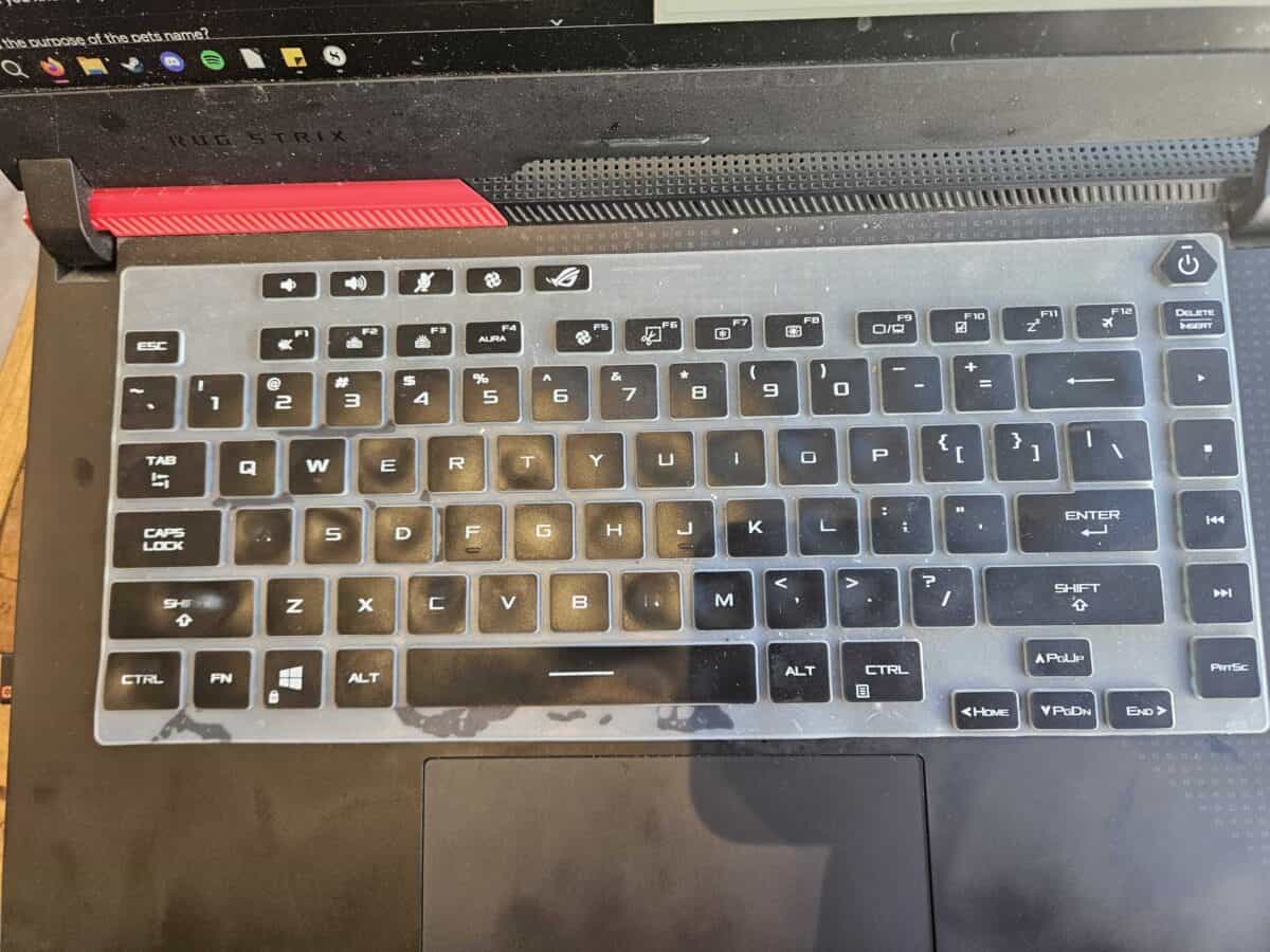 A laptop with a keyboard cover with damaged legends, making the Shift, A, and N keys unreadable.