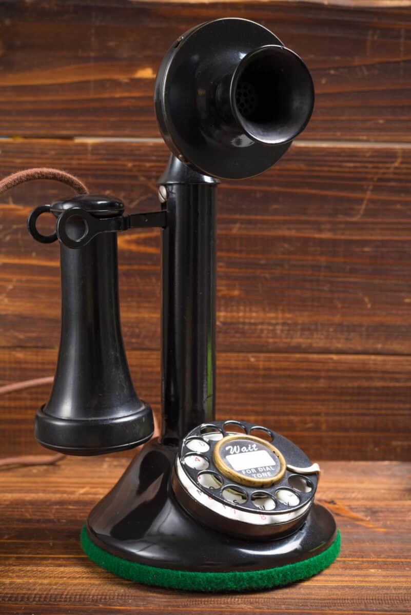 A vintage, old-fashioned, antique candlestick telephone on a wood background