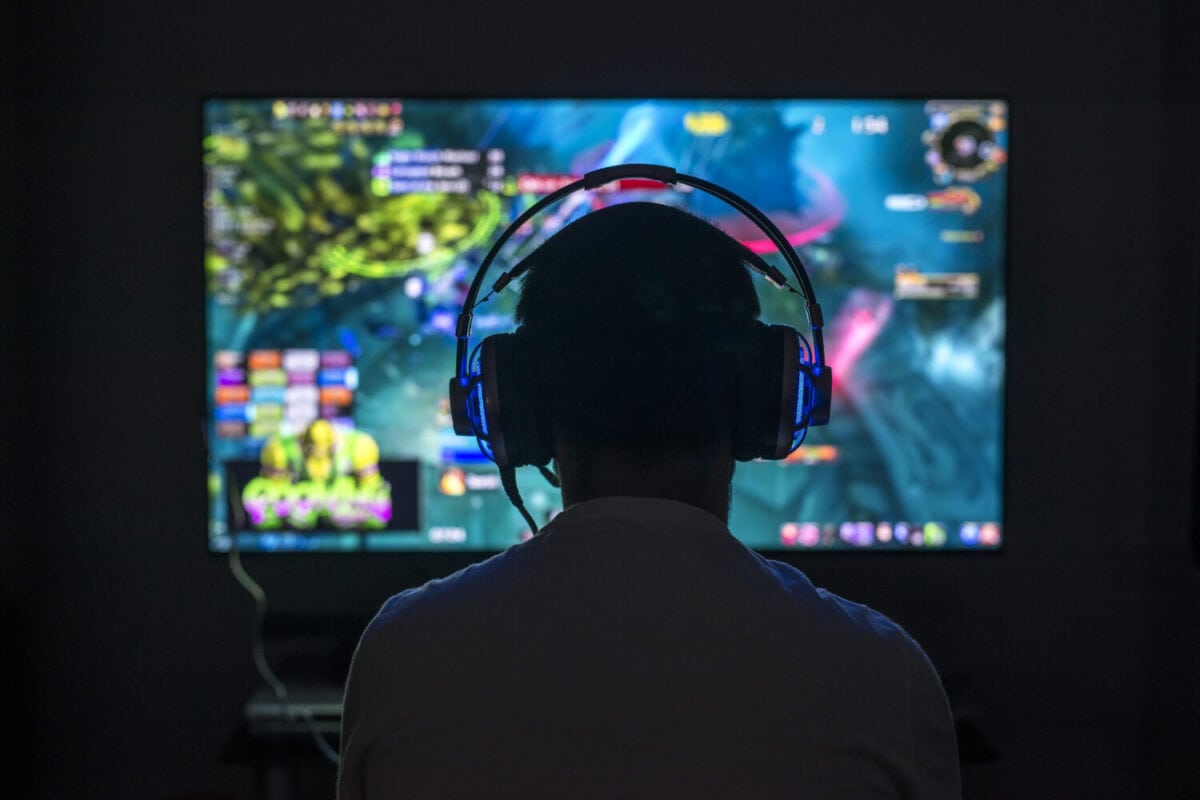 Young gamer playing video game wearing headphone.