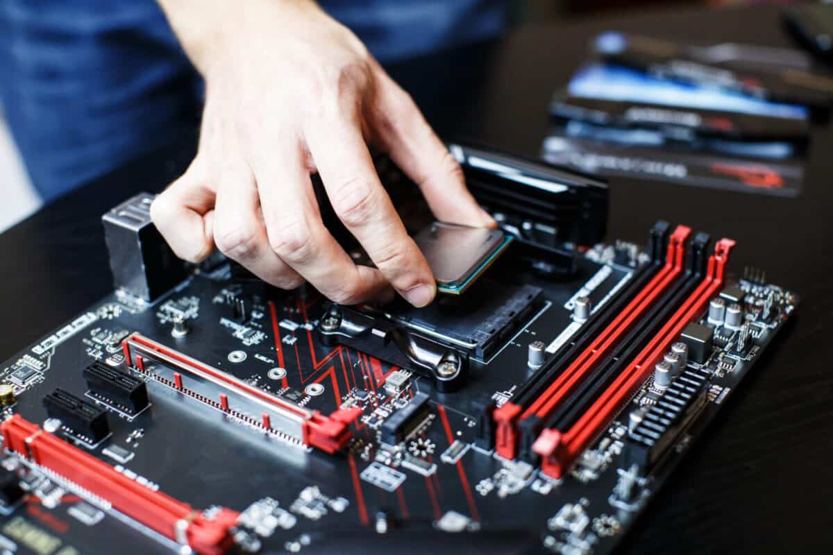 A man is assembling components to build a computer. He is putting the CPU on the socket motherboard.