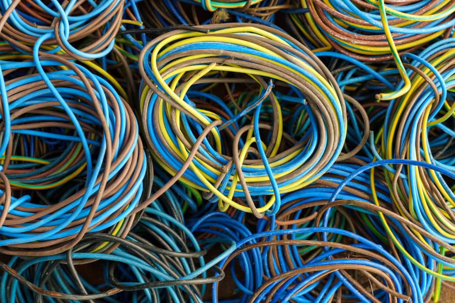 Colorful, coiled copper cables in rubber sheaths. Prepared for further recycling, copper recovery. Cables texture in full screen