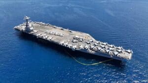 Aerial drone photo of USS Gerald R. Ford latest technology nuclear powered aircraft carrier anchored in deep blue open ocean sea