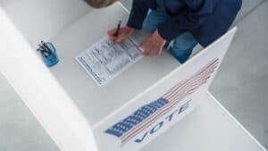 Top Down Footage of a Female Filling Out a Paper Ballot in a Voting Booth on the Day of National Elections in the United States of America. Anonymous Woman Voting for Elected Officials