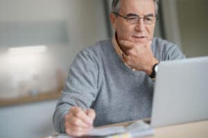 Senior man at home connected on laptop computer
