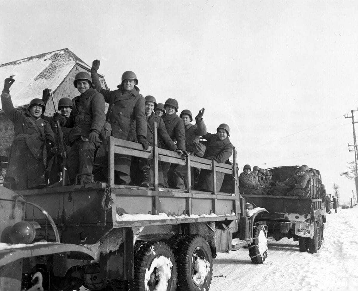 A happy group of American soldiers wave "goodbye" as they leave assembly point, first departure point, on a trip home.