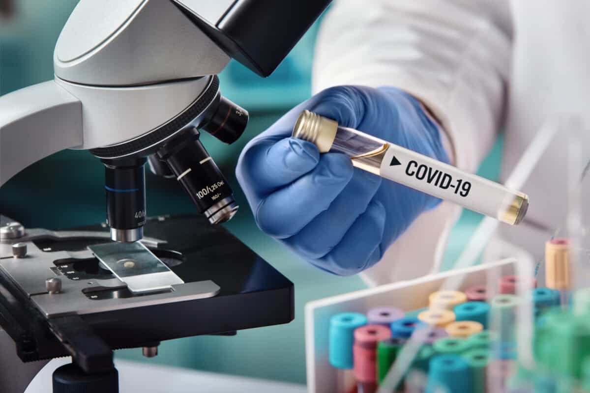 microbiologist with a tube of biological sample contaminated by Coronavirus with label Covid-19 / doctor in the laboratory with a biological tube for analysis and sampling of Covid-19 infectious disea