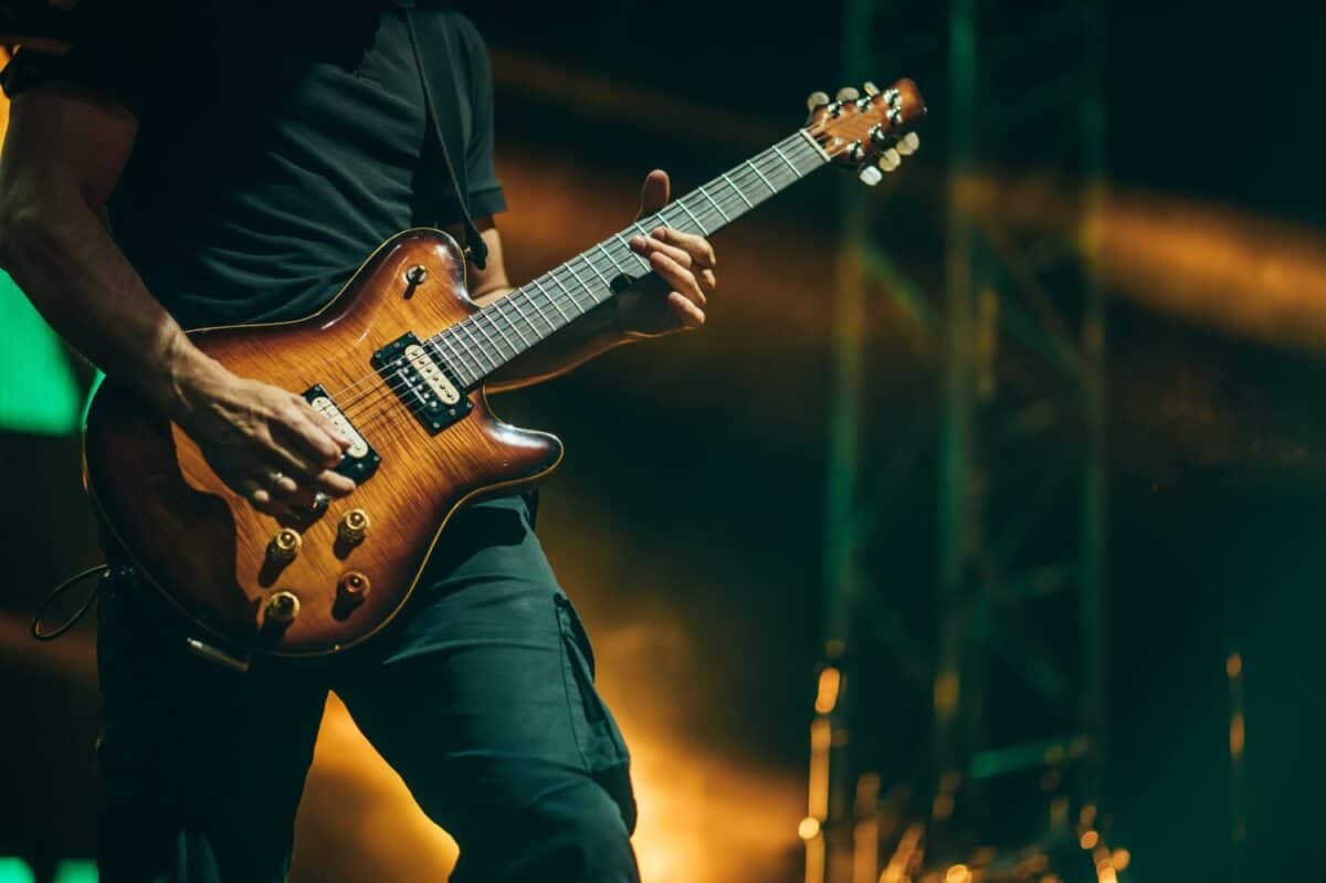 Musician playing guitar while performing on a concert on a festival