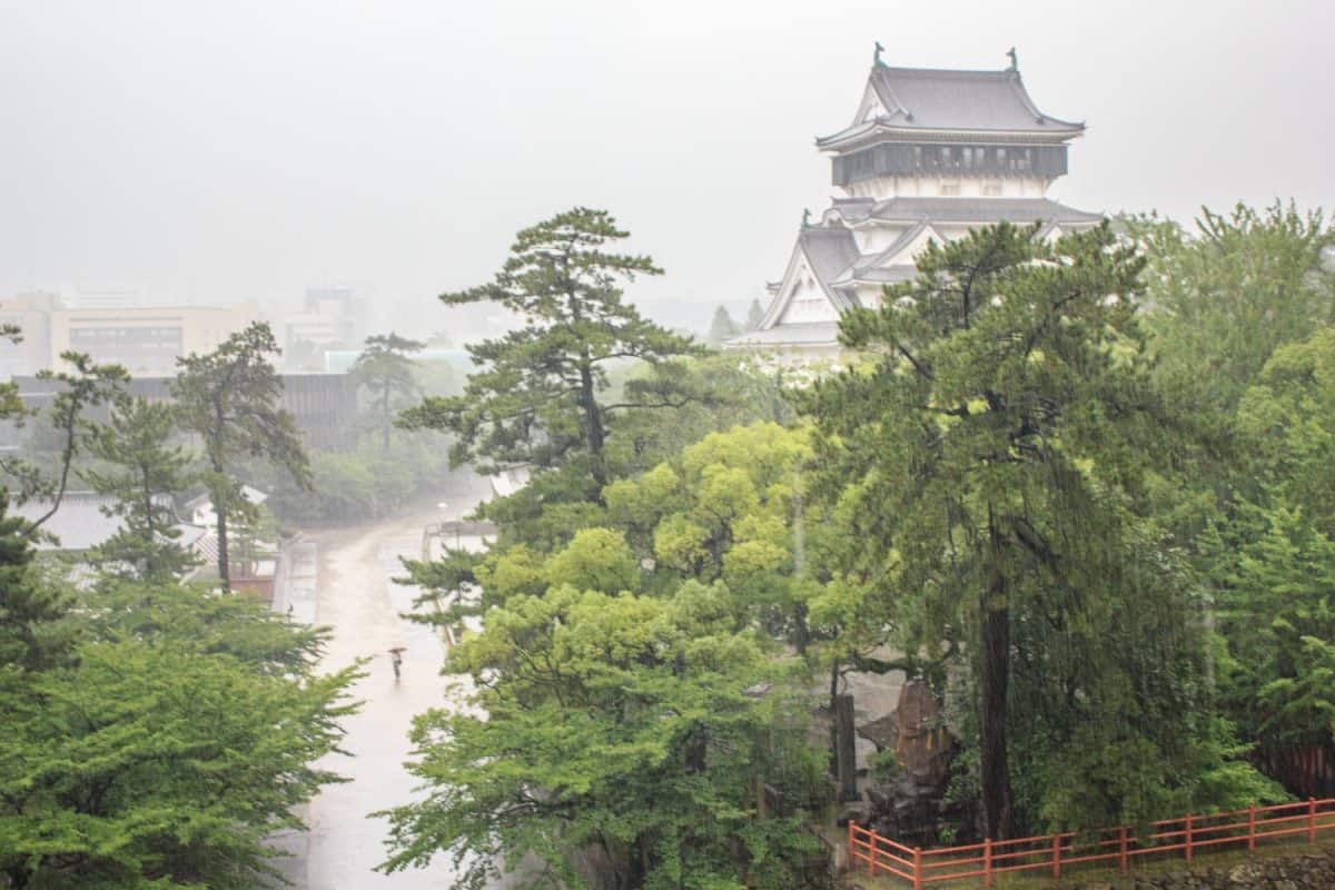 An aerial view of the white castle tower and beautiful central park in Kokura, Kyushu, Japan, during a heavy typhoon rainstorm.