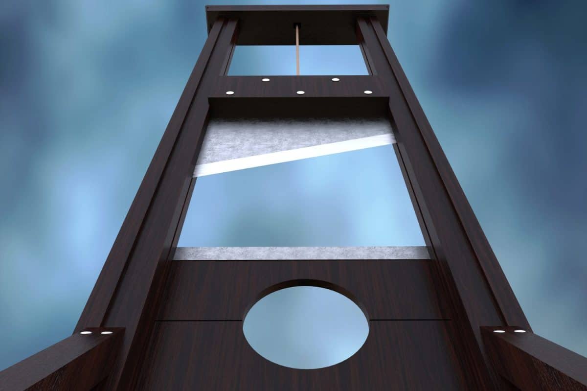 Guillotine instrument for inflicting capital punishment by decapitation and dramatic cloud background. Old wooden instrument for execution.