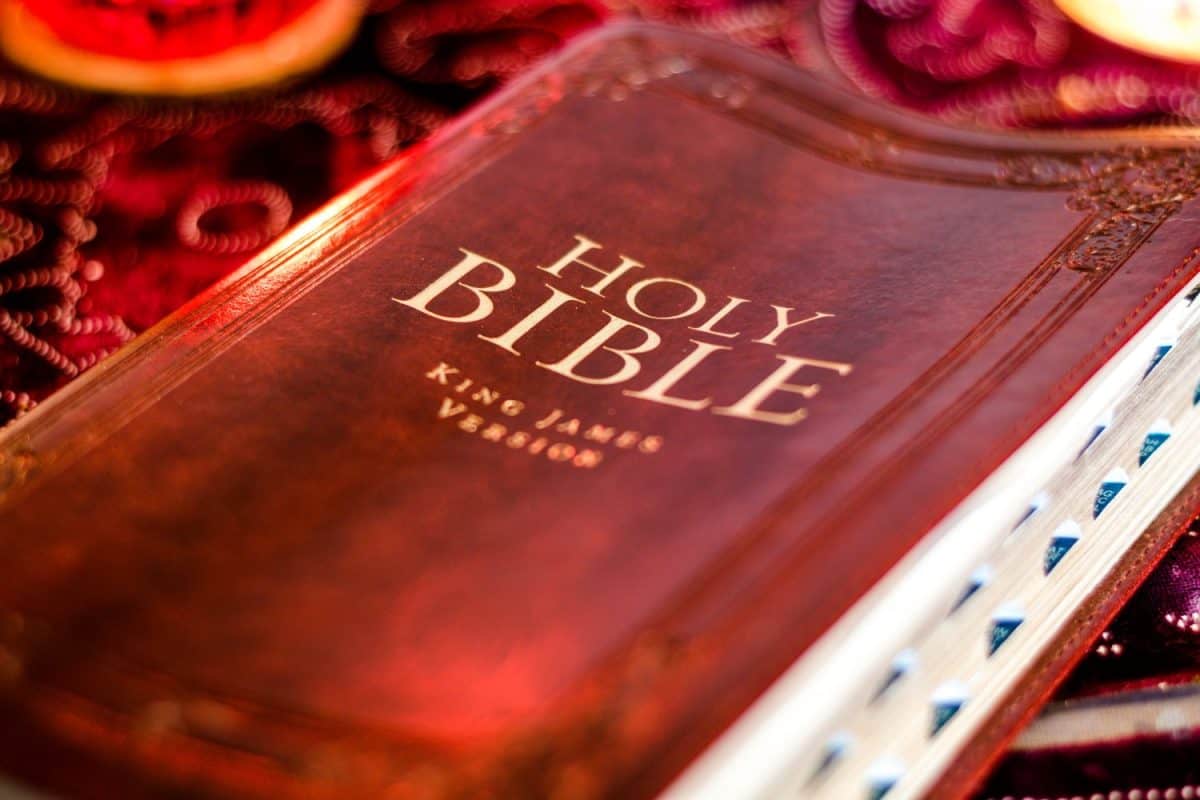 Holy Bible King James Version with pressed decorative leather cover on table with soft flickering candlelight