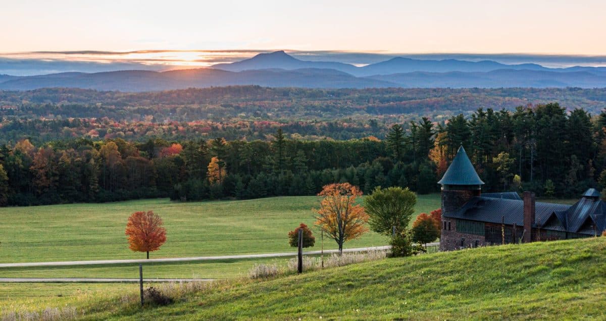 rising sun lights up Camels Hump Mountain and the Champlain Valley at Shelburne Farms historic Barn