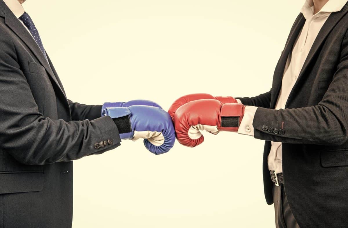 Businessmen or politicians cropped view in suits wear boxing gloves ready to fight, opposition