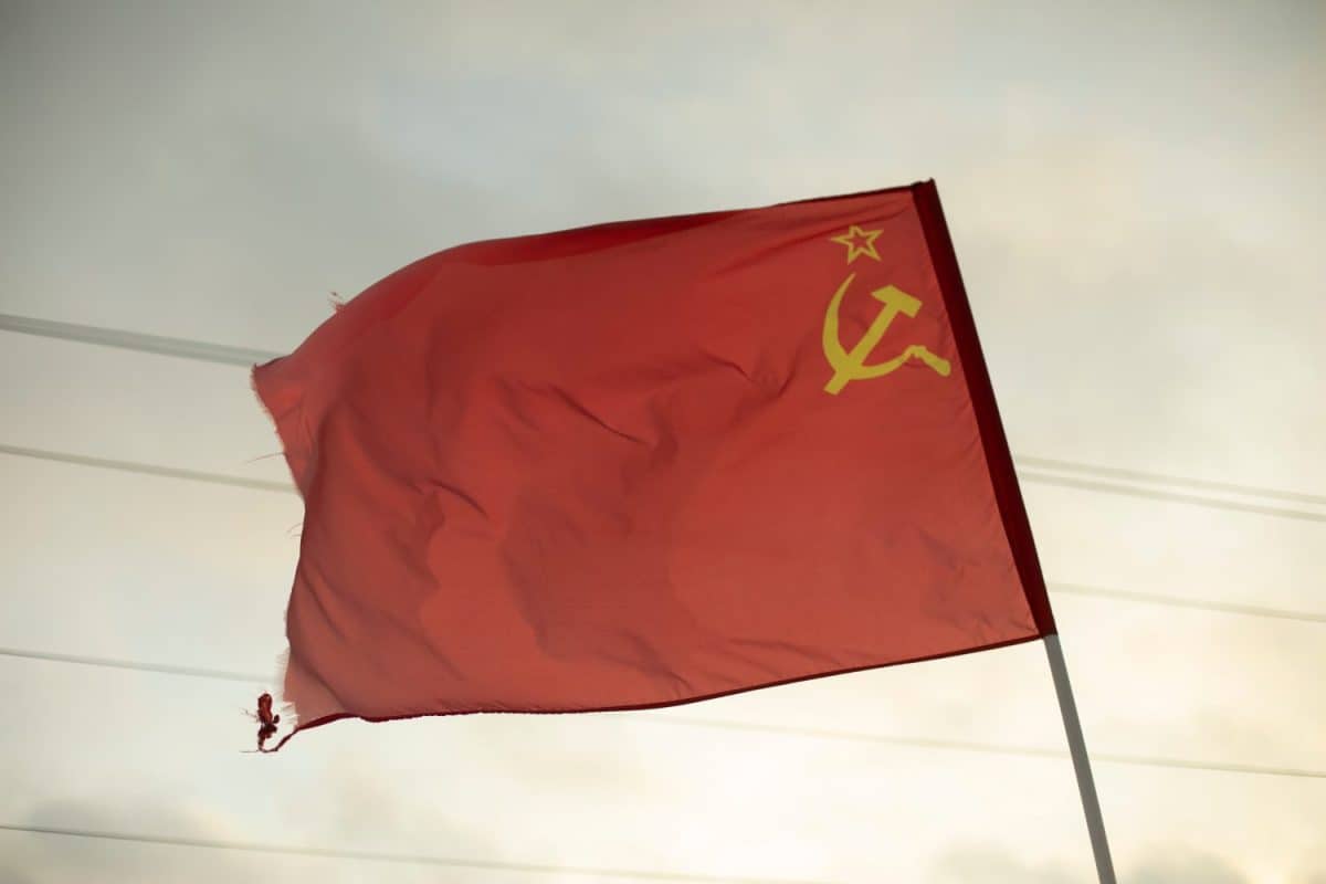 Red banner with hammer and sickle. Flag of Soviet Union. Old symbol of communist movement. Red cloth in wind.