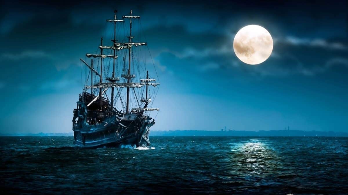 A pirate ship walking in the middle of the water in the dusk of the night with the bright moonlight