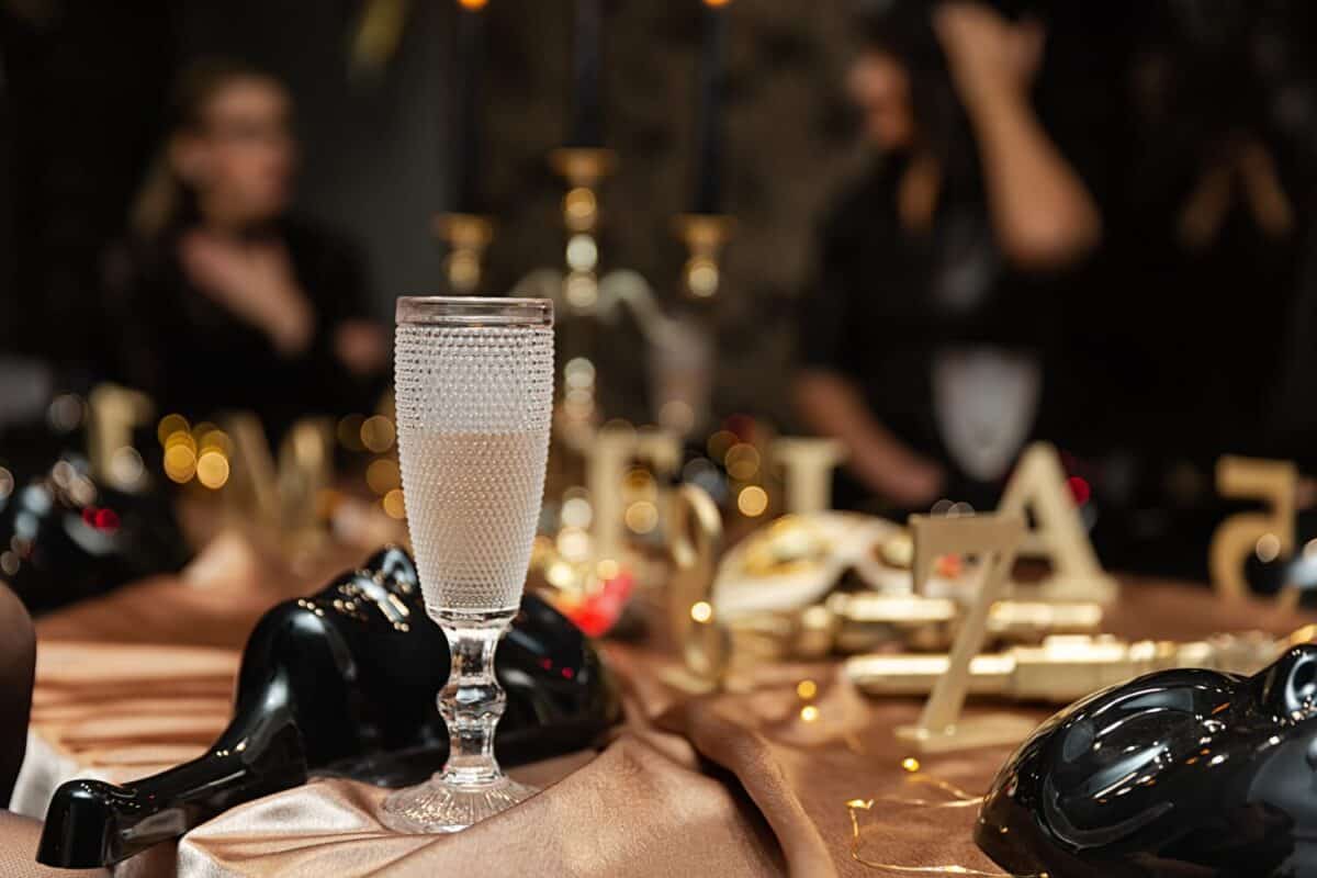 Glass of champagne and game masks on table at party