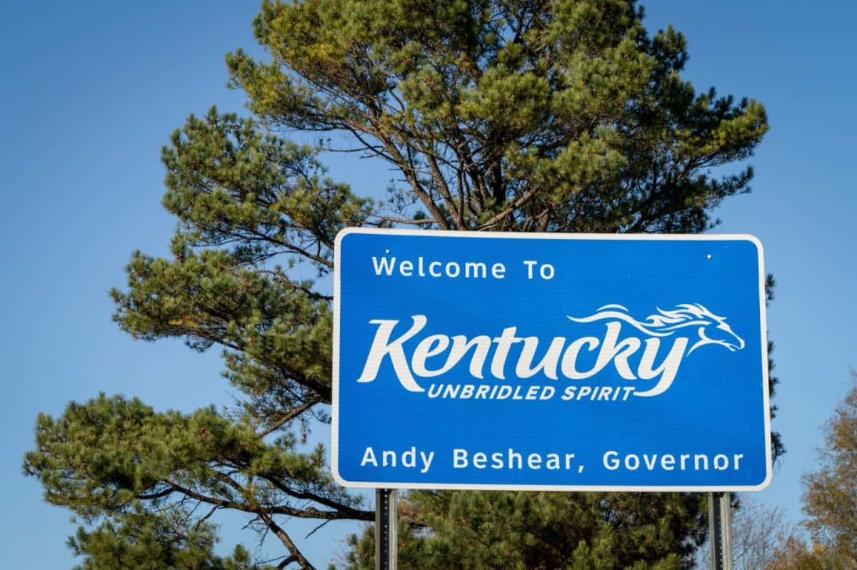 Welcome to Kentucky, Unbridled Spirit - roadsign at state border with Tennessee with a pine tree in background.