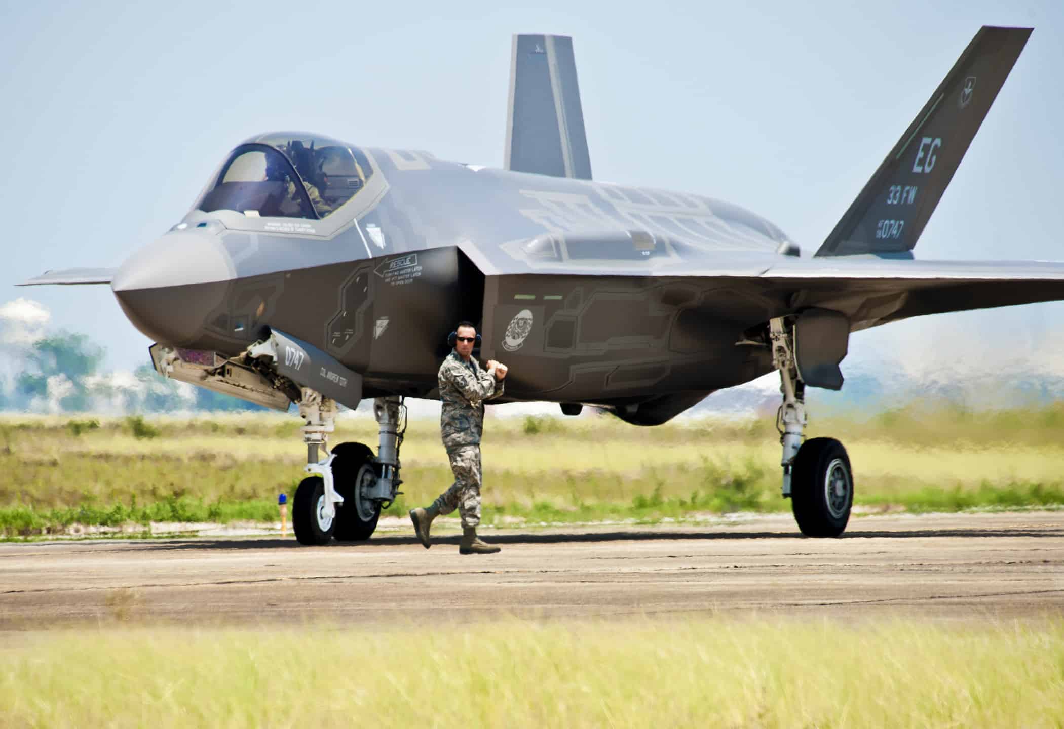 A 33rd Fighter Wing aircraft maintainer moves by the Department of Defense's newest aircraft, the U.S. Air Force F-35 Lightning II joint strike fighter (JSF), before giving the pilot the order to taxi the aircraft at Eglin Air Force Base, Fla., July 14, 2011.