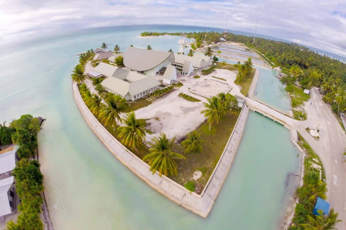 Maneaba ni Maungatabu (Parliament of Kiribati) building on motu in an atoll's lagoon, aerial view. House of Assembly, Ambo, South Tarawa, Kiribati, Gilbert islands, Micronesia, Oceania.