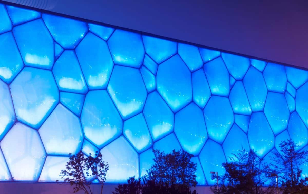 The exterior of the National aquatic center in Olympic park in Beijing China lit up at night blue.