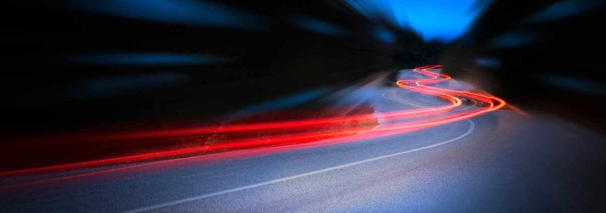 Panoramic - Cars light trails at night in a curve asphalt road at night, long exposure image