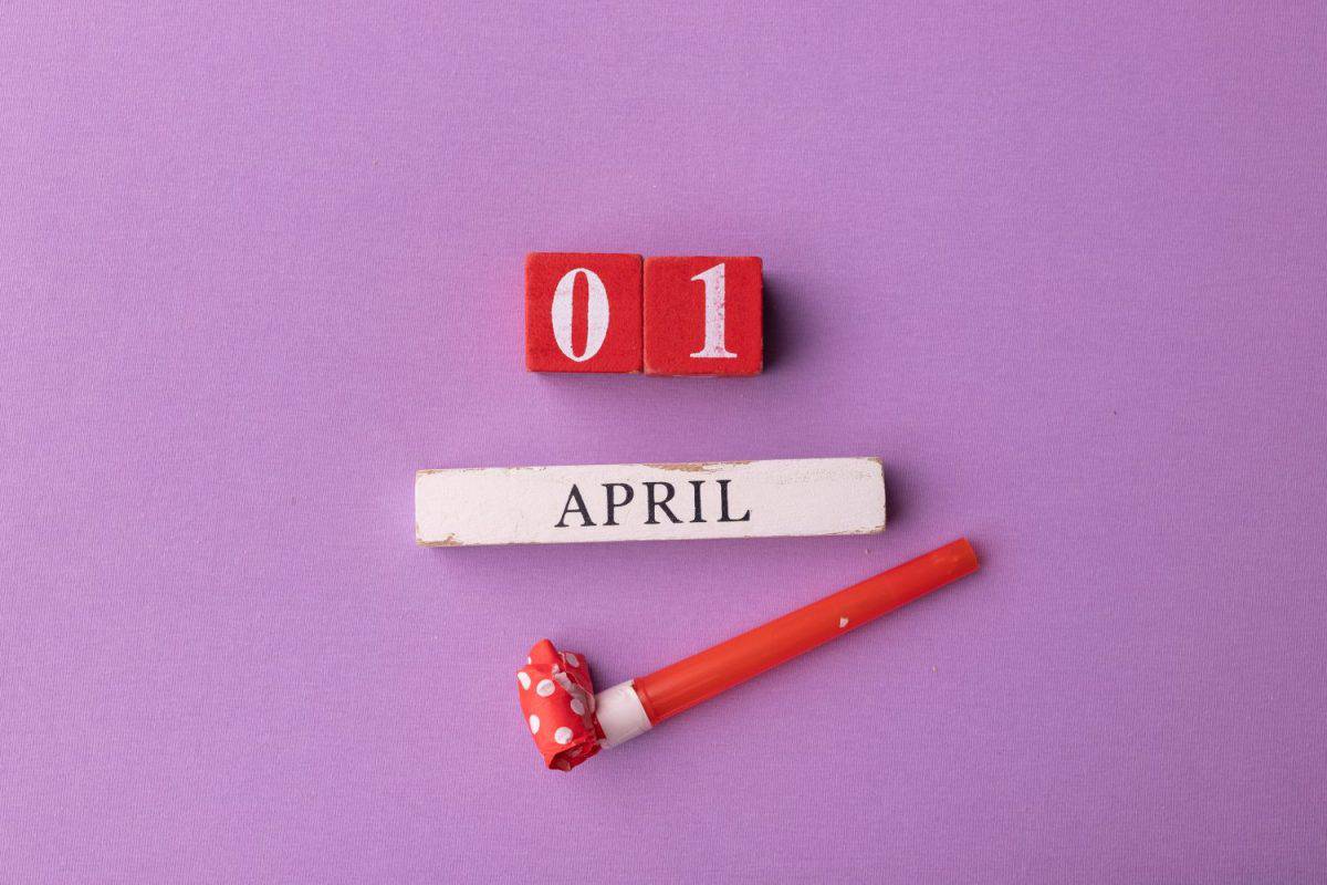 April 1st. Image of april 1 wooden calendar and festive decor on the pink background. April Fool's Day.