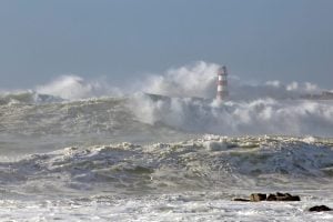Beacon and pier of Povoa do Varzim e Vila do Conde fishing harbor and marina under heavy storm with strong wind and big waves, north of Portugal.