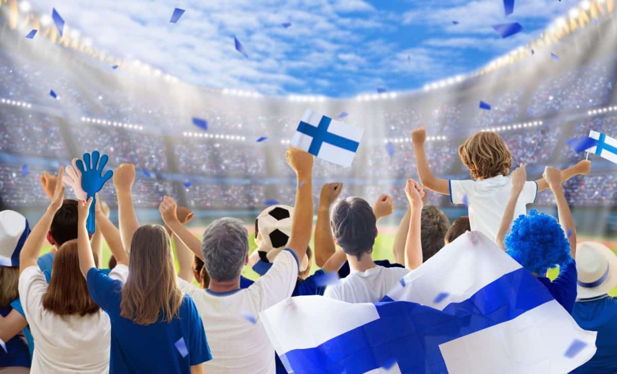 Finland football supporter on stadium. Finnish fans on soccer pitch watching team play. Group of supporters with flag and national jersey cheering for Suomi. Championship game.