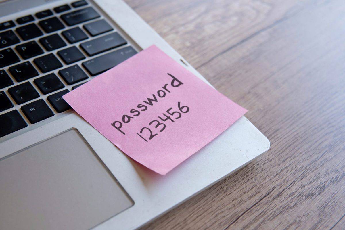 Sticky note with the word "password 123456" on a laptop keyboard. Data protection, password strength concept.
