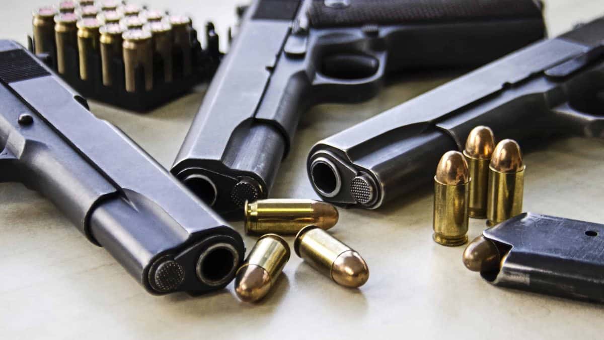 Three pistols laying on table with bullets