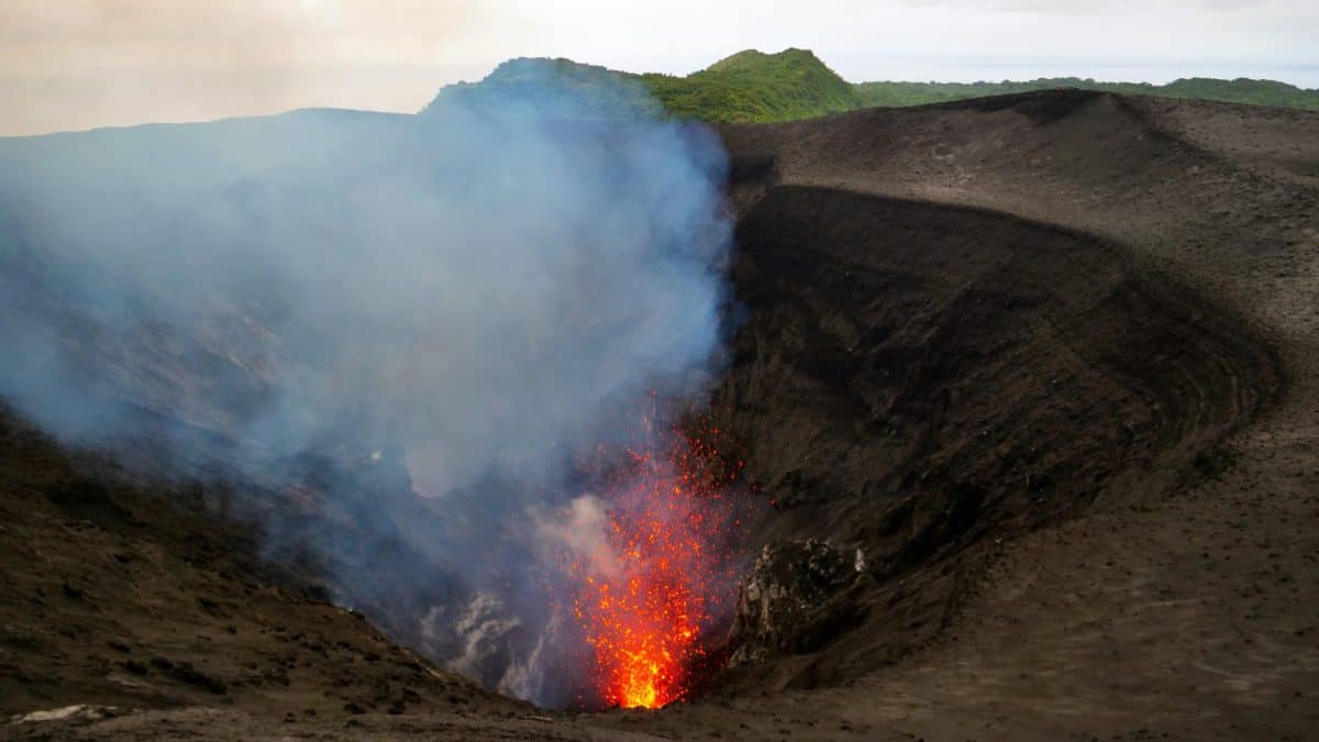 Breathtaking view from above of the roaring depths of an active volcano in Tanna. Stunning shot of Mount Yasur spewing out glowing lava high in the air. Volcanic crater erupting and emitting lava
