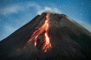 Merapi volcano eruption, hot lava flows on the slope at night.