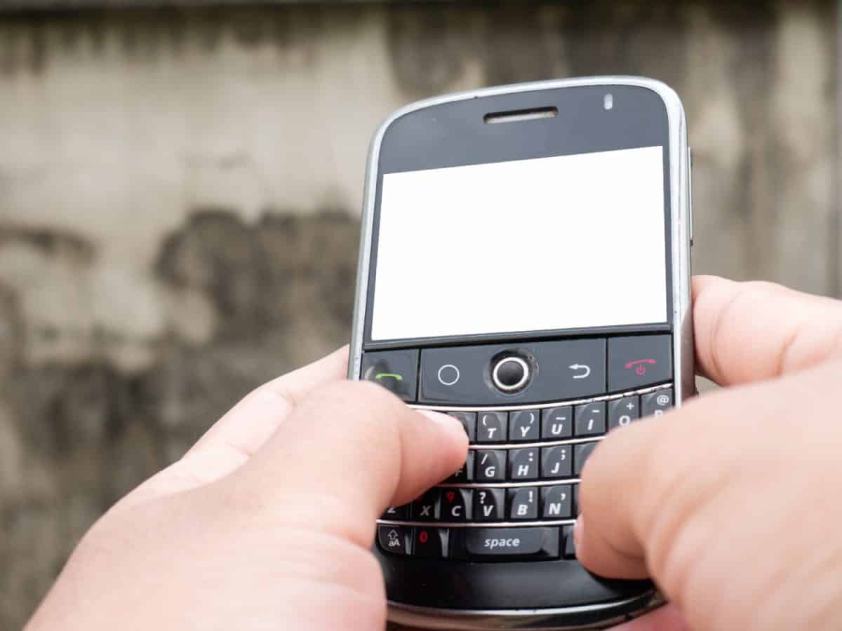 A man typing message on mobile phone with qwerty keyboard. Cellphones with blank display.