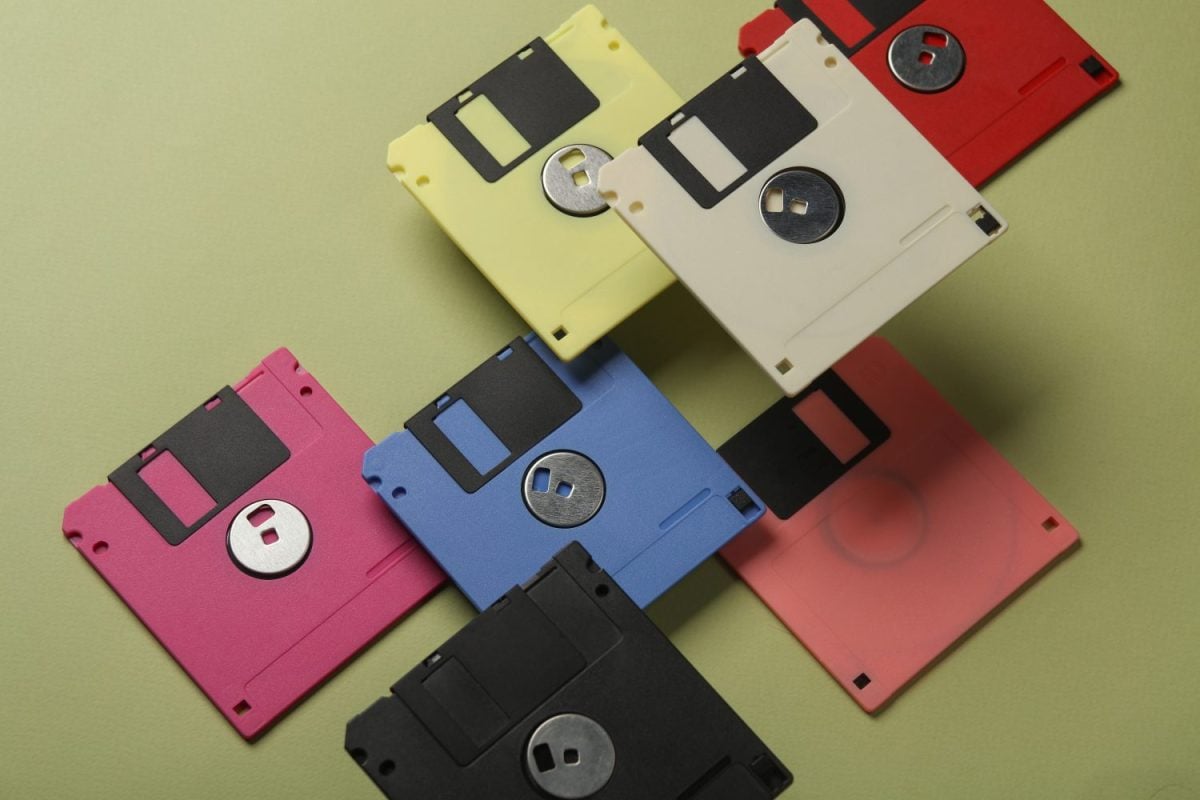 Floating colored retro 80s floppy disks on a green background. Conceptual pop, creative layout