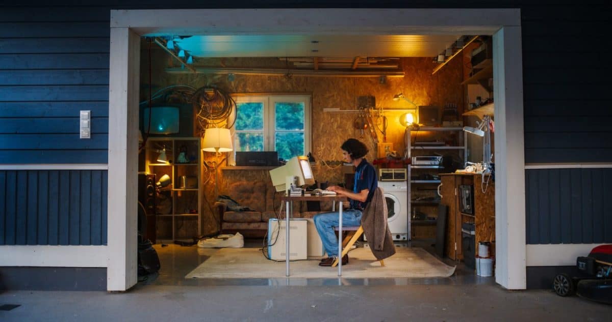 Caucasian Male Software Engineer Programming On Old Desktop Computer In Retro Garage In The Evening. Ambitious Man Starting an Innovative Fintech Startup Company In Nineties. Nostalgia Concept.