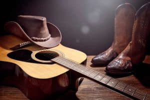 Country music festival live concert with acoustic guitar, cowboy hat and boots background