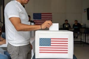 hispanic man placing his vote ballot in the polling box in the us elections of usa, cituzen voting in america 2024