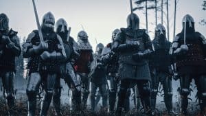 Epic Invading Army of Medieval Knights on Battlefield. Armored Soldiers in Helmets, With Shields and Swords ready for the Battle. War, Conquest, Crusade. Historical Reenactment.