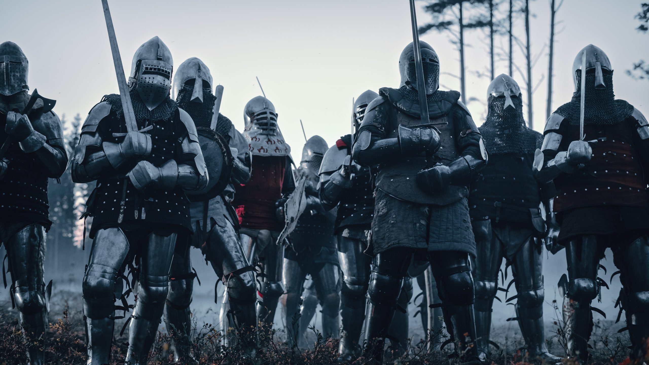 Epic Invading Army of Medieval Knights on Battlefield. Armored Soldiers in Helmets, With Shields and Swords ready for the Battle. War, Conquest, Crusade. Historical Reenactment.