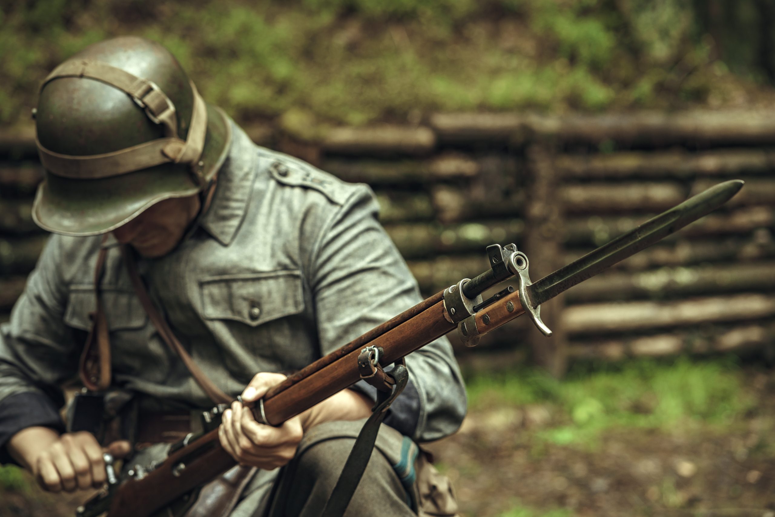 Military reconstruction of the Finnish army during World War II. A soldier with a rifle and a bayonet knife is sitting in a trench. Summer military uniform.
