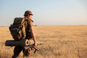 military man with a backpack in the field. Soldier goes on a mission. Back view