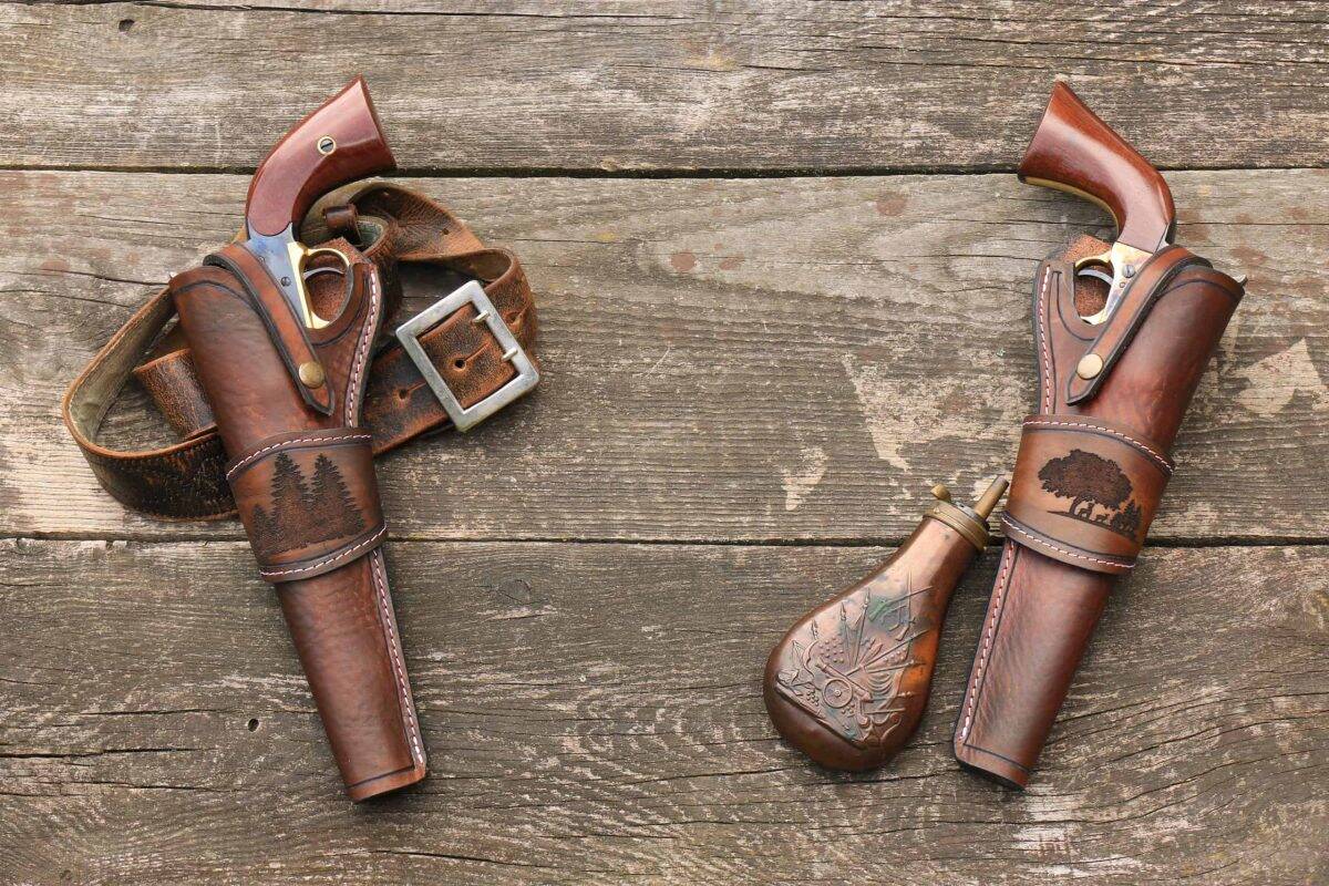 Black powder revolvers in a leather holster with a leather belt and gunpowder flask on the background of old, worn boards.