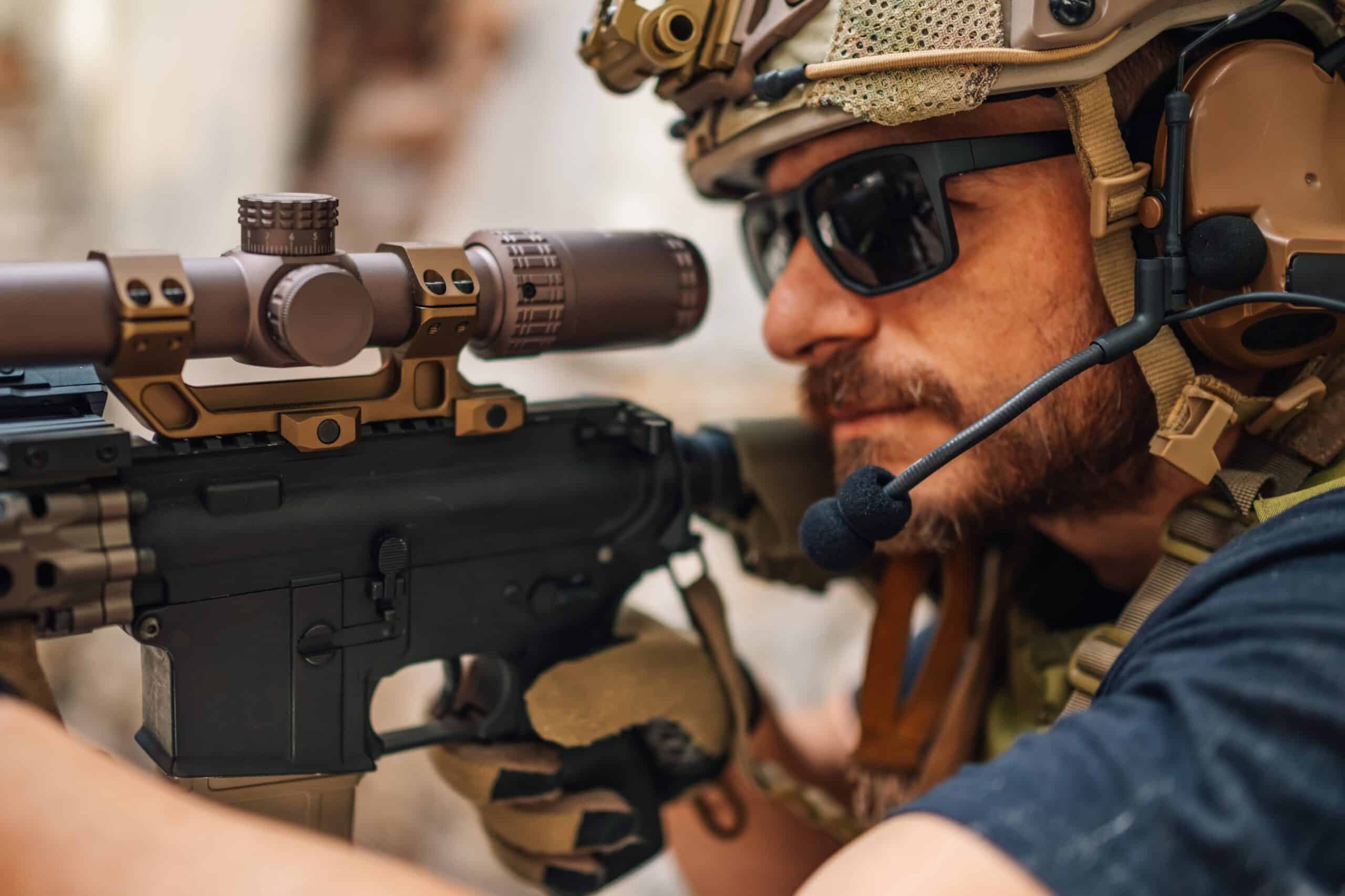 Close up of brave soldier aiming with sniper rifle at opponent. Soldier at warzone defending his side on battlefield. Courageous soldier shooting and aiming with sniper rifle. Soldier on a mission.