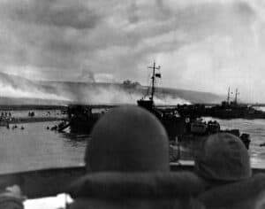 Silhouetted by helmets, view shows two landing craft at Omaha beach on D-Day. Each large ship landed 200 soldiers. June 6, 1944, World War 2.