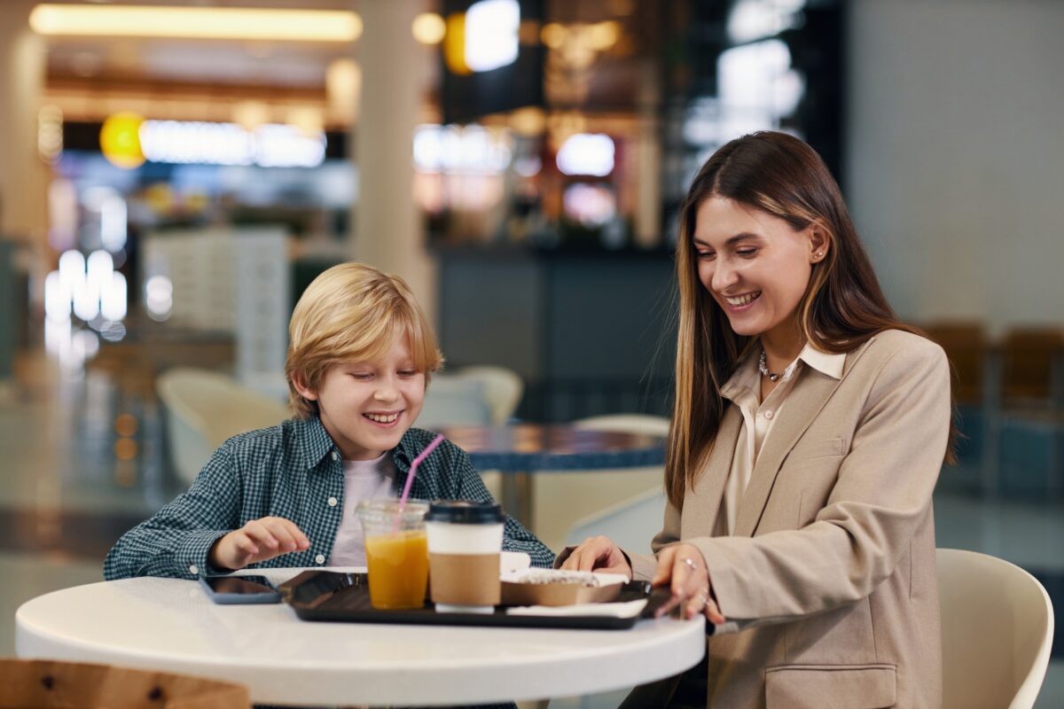 Medium shot of brunette mom taking tray full of beverages and hot delicious food to have lunch after shopping