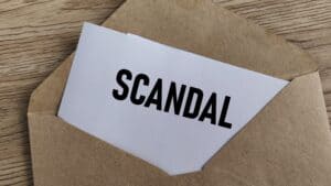 Scandal Revealed: Confidential Information Paper with Text Emerging from a Brown Manila Envelope on Wood Desk