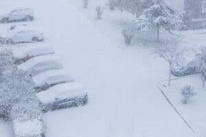 High angle view of cars parked in a residential parking lot covered with thick white snow during a winter blizzard.