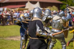 Knights in armor fight on the battlefield. Reconstruction of an ancient tournament of the 15th century.